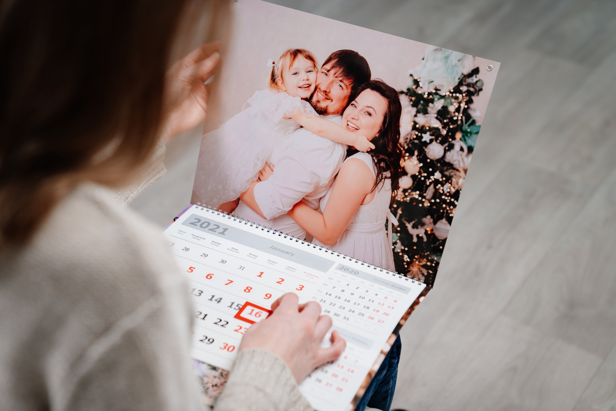 A woman marking a date on a calendar beside a family photograph