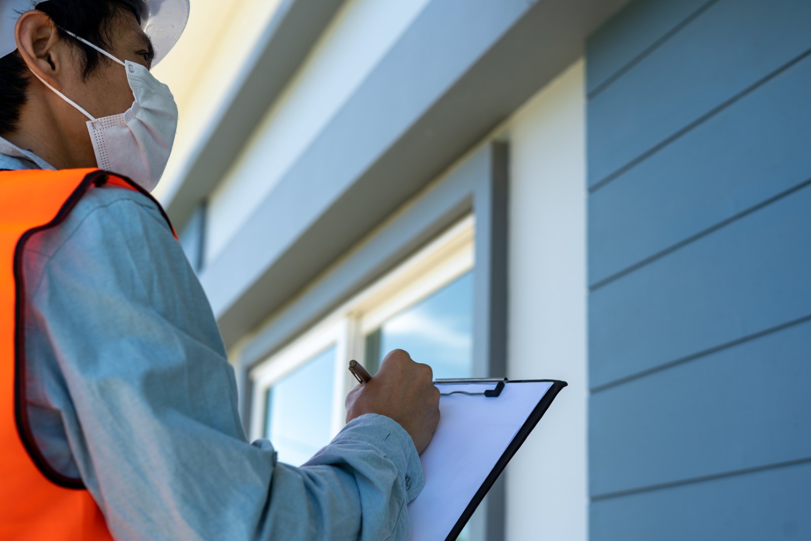 An inspector reviews a house with a checklist on a clipboard
